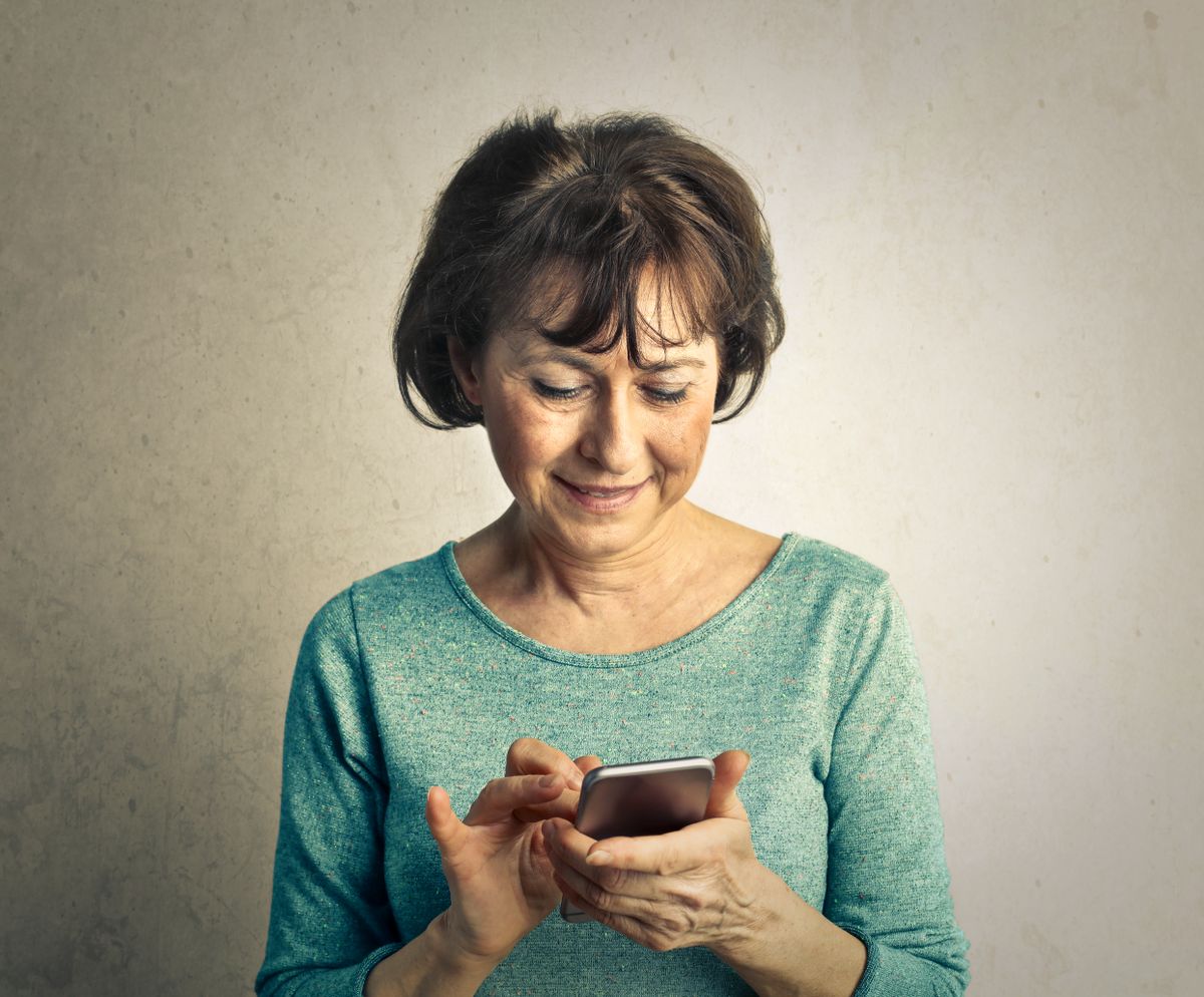 A senior woman enjoying a lighthearted moment using her smartphone