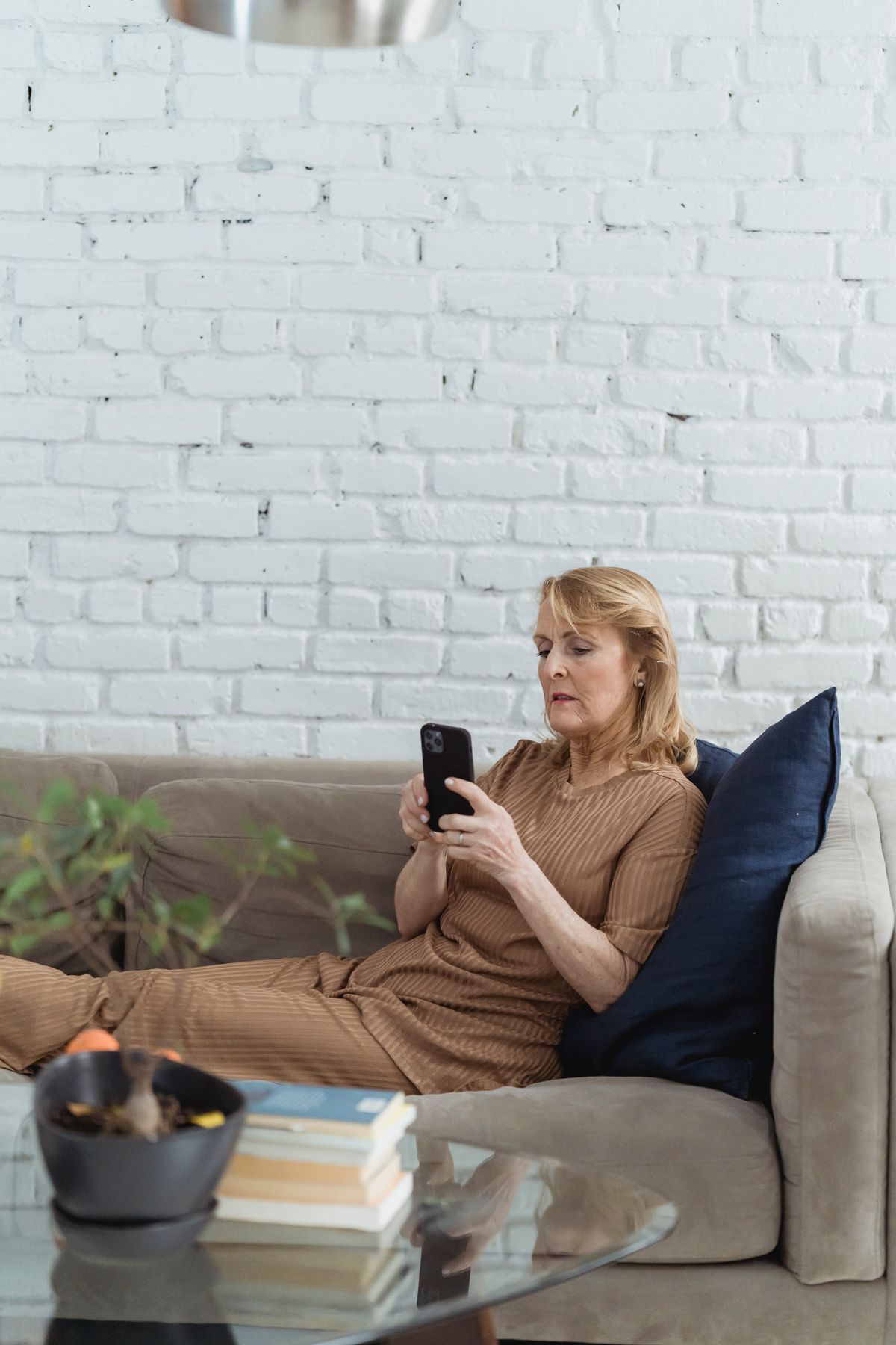 An elderly woman comfortably texting on her phone while seated at home